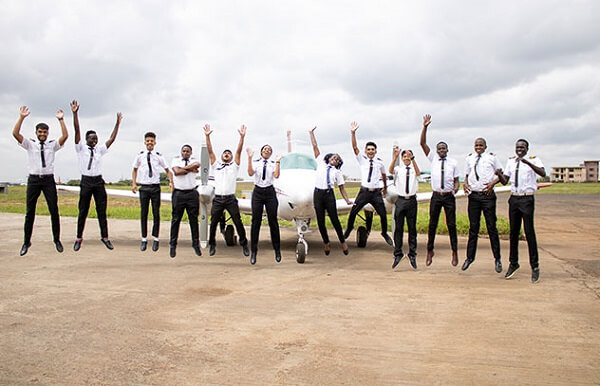 Proactive Training Services Students take a jumping photo in front of a plane